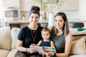 Two mothers reading a book with their toddler