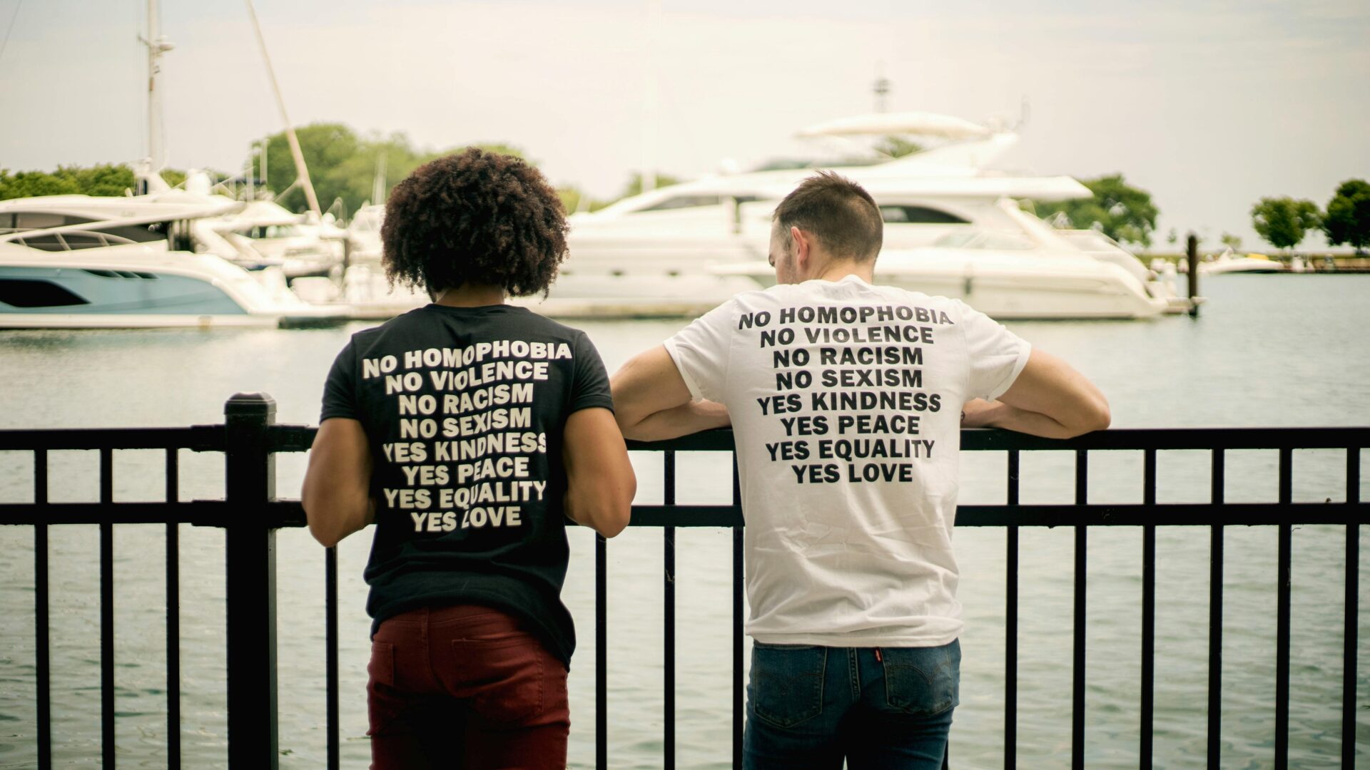 Men leaning on a rail overlooking water and a boat.