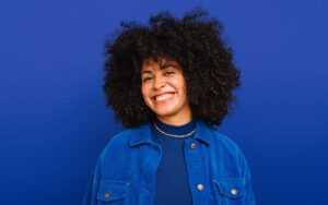 Image shows a smiling person in a blue outfit against a blue background.