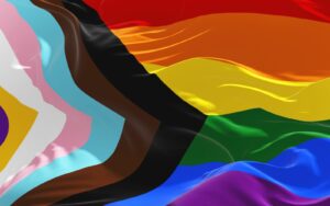 A close up of the LGBTQ+ progress pride flag flapping in the wind